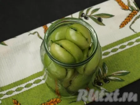 Заполнить банки зелёными помидорами, фаршированными чесноком и петрушкой, до самого верха.